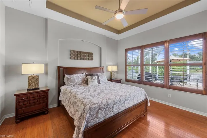 Bedroom with a tray ceiling, hardwood / wood-style floors, and a ceiling fan