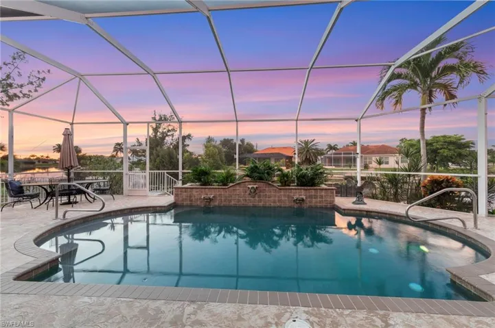 Pool at dusk featuring an outdoor pool, a sunroom, and glass enclosure