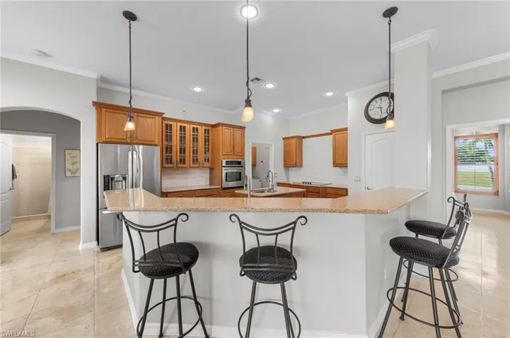 Kitchen with tasteful backsplash, a breakfast bar, stainless steel appliances, pendant lighting, and arched walkways