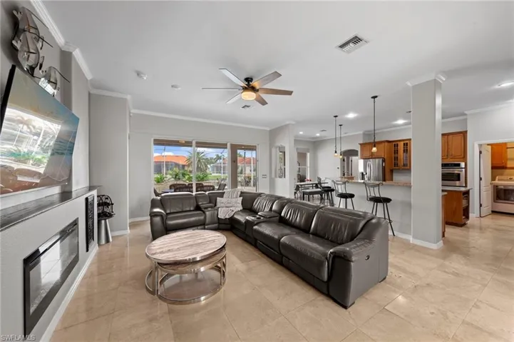 Living area featuring crown molding, ceiling fan, and light tile patterned floors