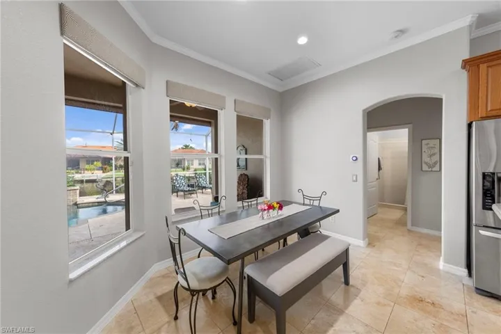 Dining space with crown molding, arched walkways, light tile patterned flooring, and recessed lighting