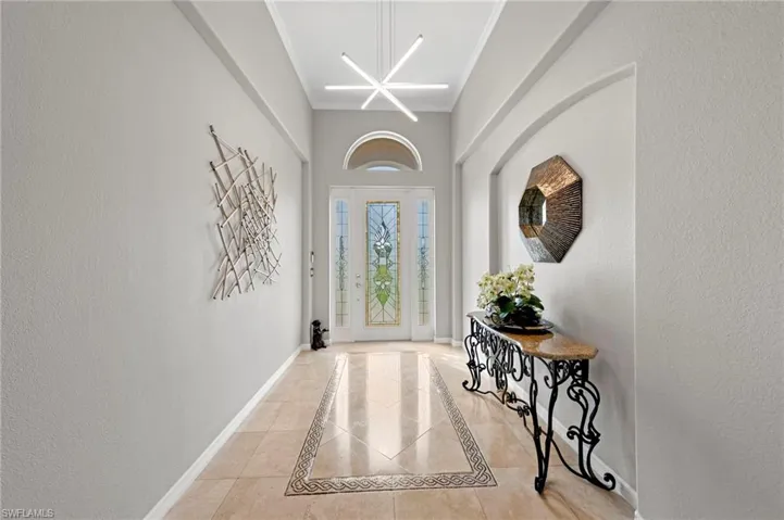 Foyer with a textured wall, a chandelier, and inlaid floor details