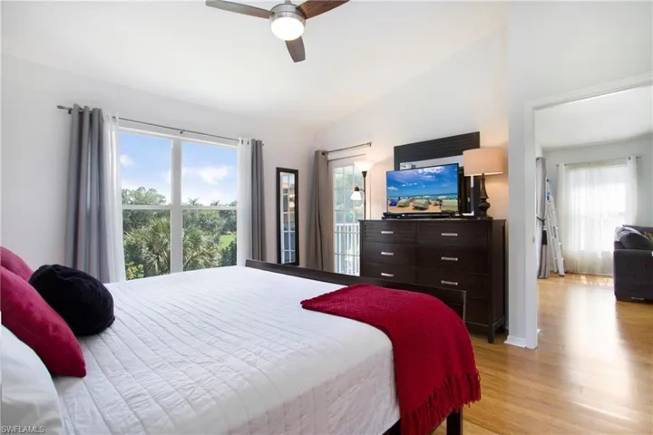 Bedroom featuring vaulted ceiling, light wood finished floors, access to exterior, and ceiling fan