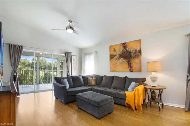 Living area featuring lofted ceiling, wood finished floors, and a ceiling fan