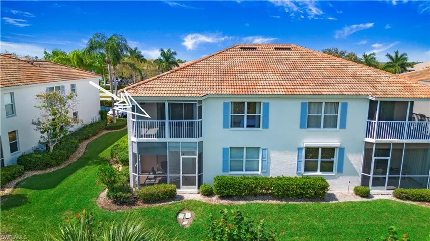 Rear view of house featuring a sunroom, a yard, stucco siding, a balcony, and a tile roof