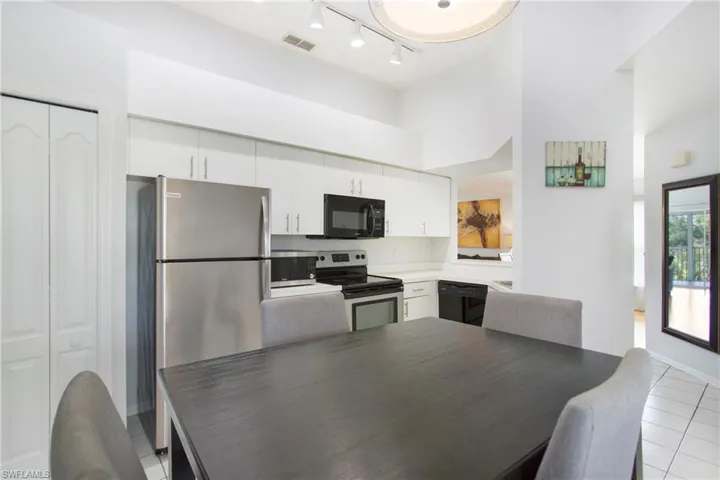 Dining room featuring a towering ceiling, light tile patterned flooring, and track lighting