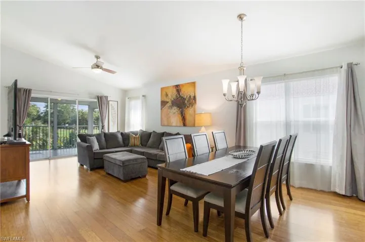 Dining area with light wood finished floors, lofted ceiling, ceiling fan, and a chandelier