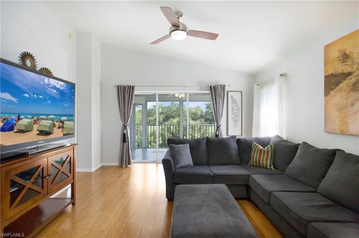 Living room featuring vaulted ceiling, light wood-style floors, and a ceiling fan