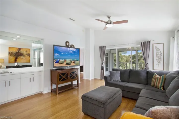 Living area featuring light wood-style flooring, vaulted ceiling, and a ceiling fan