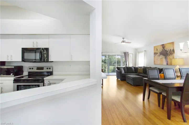 Kitchen featuring appliances with stainless steel finishes, vaulted ceiling, light countertops, white cabinetry, and light wood-style flooring