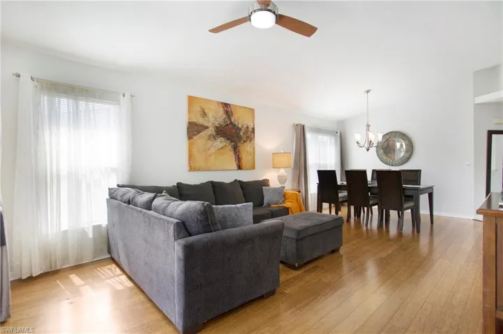 Living area with lofted ceiling, light wood-style floors, a chandelier, and a ceiling fan