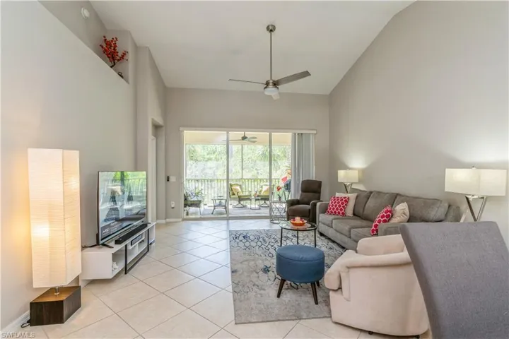Living room featuring high vaulted ceiling, ceiling fan, and light tile floors