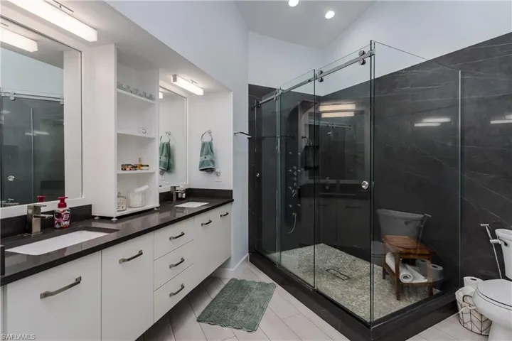 Full bath featuring double vanity, a shower stall, and light tile patterned floors