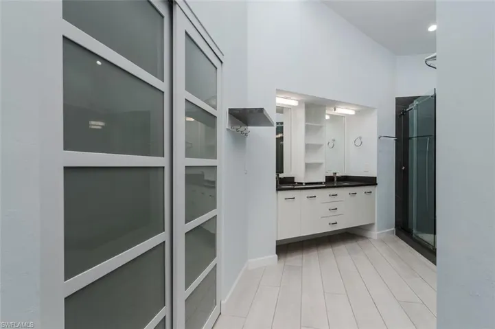 Full bathroom with a stall shower, double vanity, and light wood-type flooring