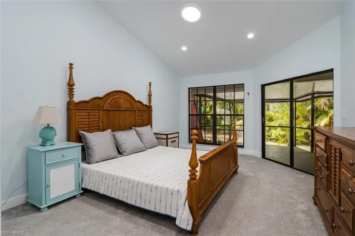 Bedroom with light carpet, lofted ceiling, and access to outside
