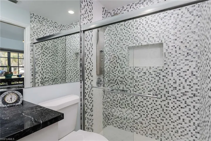 Full bath featuring a shower stall and toilet