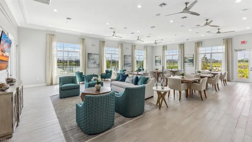 Spacious common area featuring large windows, light-toned flooring, and ceiling fans