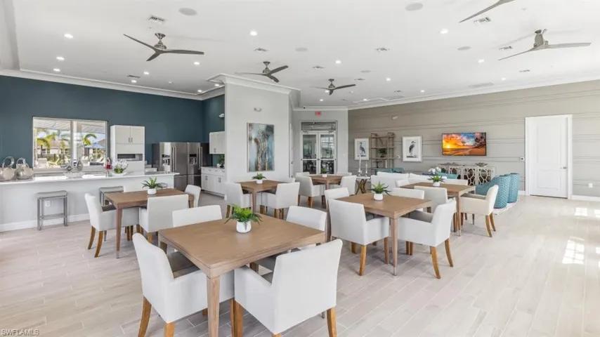 The property features a spacious common area with light-toned flooring, multiple ceiling fans, and a kitchen area equipped with stainless steel appliances