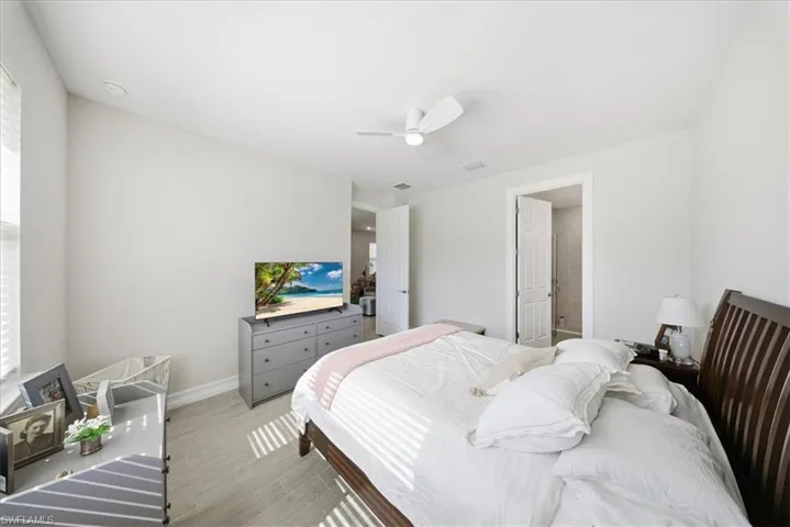 Bedroom featuring wood finished floors, a ceiling fan, and connected bathroom