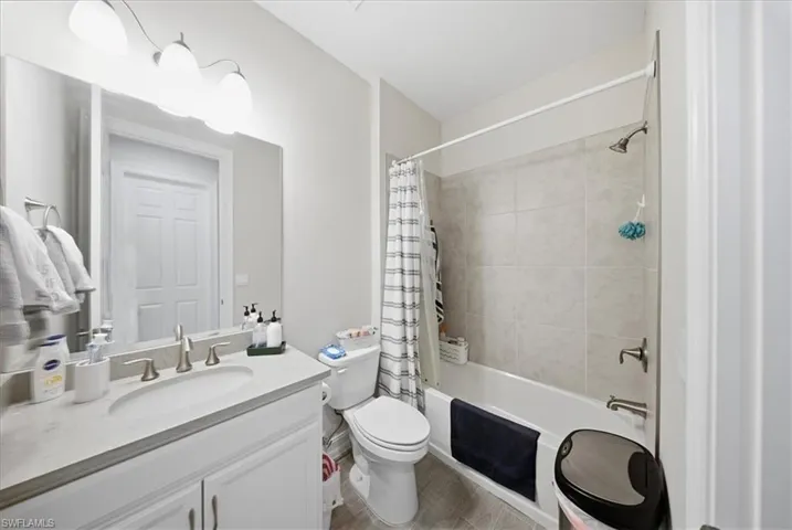 Full bathroom with vanity, shower / bath combo with shower curtain, and light wood-style floors