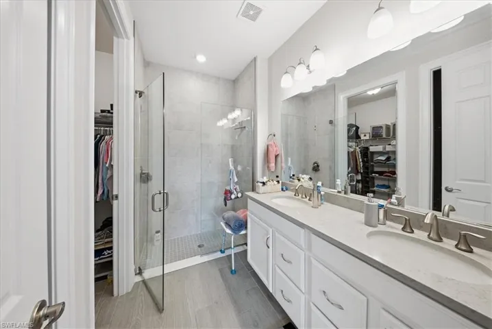 Full bathroom with a walk in closet, double vanity, and a stall shower
