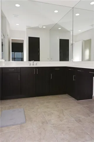 Expansive countertop with an undermount sink, dark wood-finish cabinetry, and full wall mirrors
