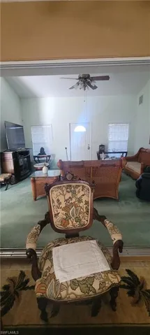 Carpeted living area featuring ceiling fan