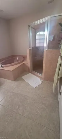 Full bath with a shower stall, light tile patterned flooring, and a garden tub