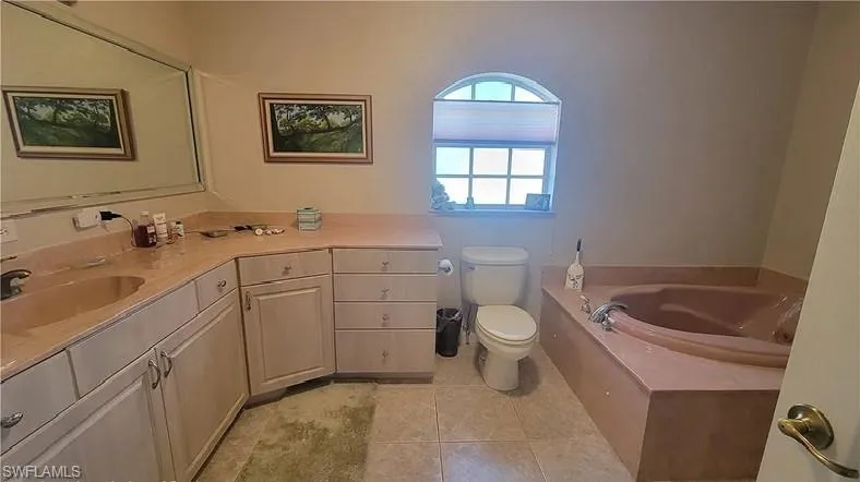 Full bath with vanity, a garden tub, and light tile patterned floors