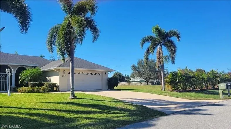 View of side of home with driveway, a lawn, stucco siding, and an attached garage