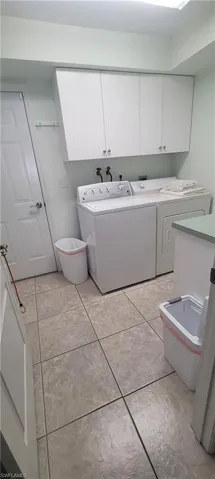 Bathroom with independent washer and dryer, light tile patterned floors, and vanity