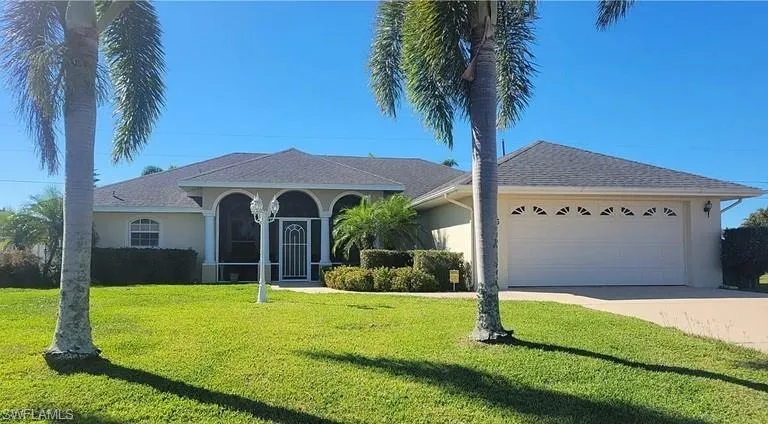 View of front of home with stucco siding, a front lawn, concrete driveway, an attached garage, and roof with shingles