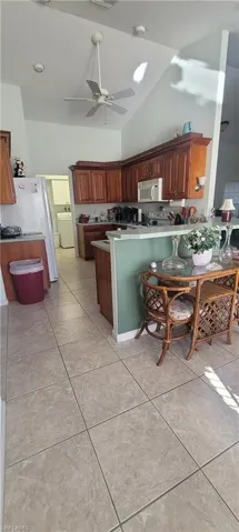 Kitchen featuring a peninsula, a ceiling fan, lofted ceiling, white appliances, and washer / clothes dryer
