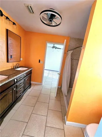 Full bathroom featuring a shower with shower curtain, a ceiling fan, visible vents, a sink, and tile patterned flooring
