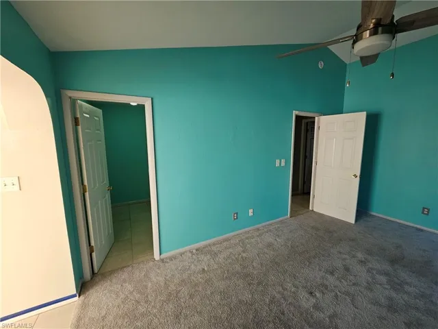 Unfurnished bedroom featuring baseboards, a ceiling fan, lofted ceiling, and carpet floors