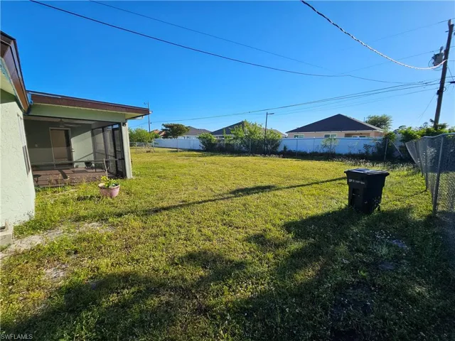 View of yard featuring fence and a sunroom