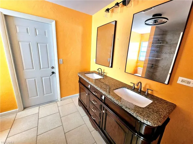 Full bathroom with tile patterned flooring, double vanity, baseboards, and a sink