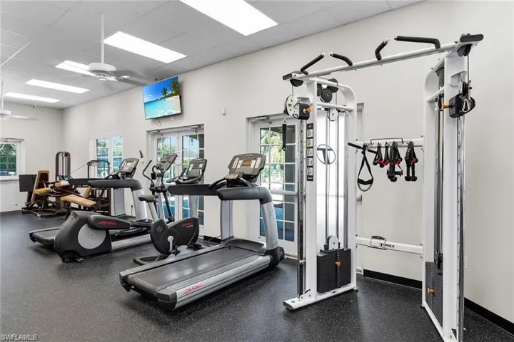 Dedicated fitness room featuring cardio equipment, strength training machines, and a multi-station cable system