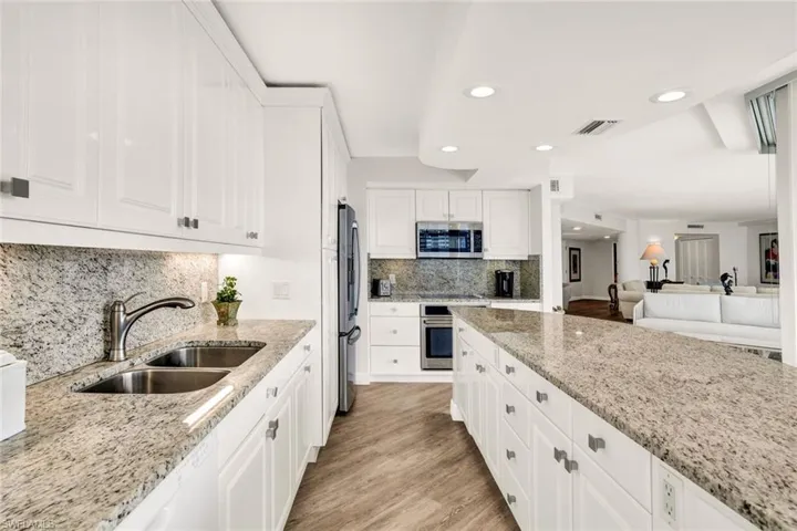 Kitchen featuring light stone counters, a sink, stainless steel appliances, light wood-style flooring, and visible vents