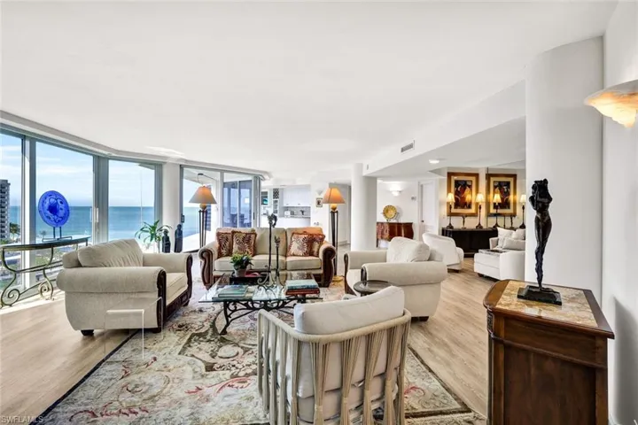 Living room featuring a wall of windows, light wood-style flooring, visible vents, and a water view