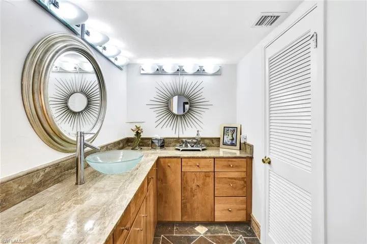 Full bath with stone finish floor, visible vents, a sink, and double vanity