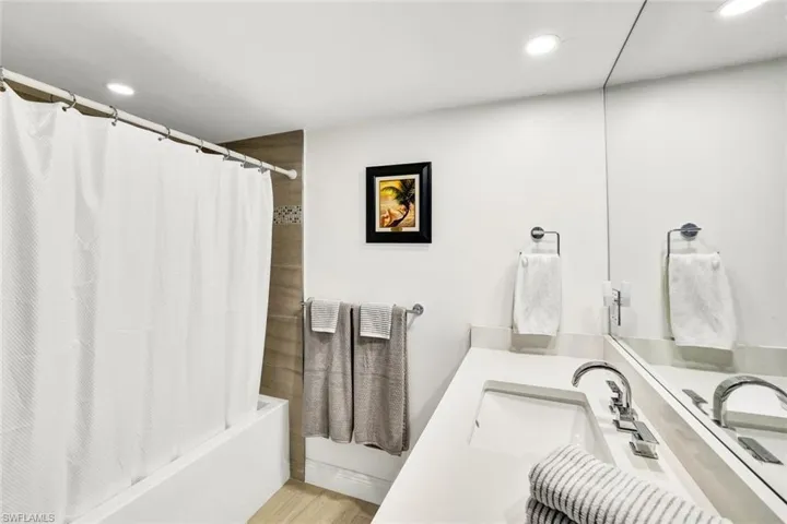 Bathroom featuring recessed lighting, wood finished floors, vanity, and shower / bathtub combination with curtain
