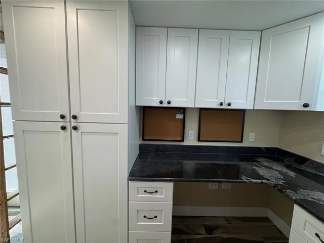 Kitchen with white cabinets and dark stone countertops