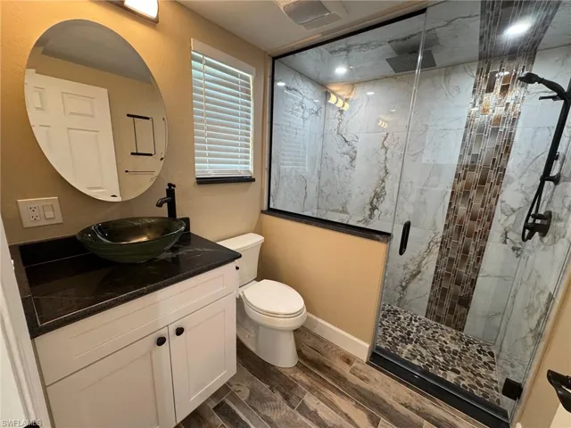 Bathroom featuring hardwood / wood-style flooring, vanity, toilet, and walk in shower