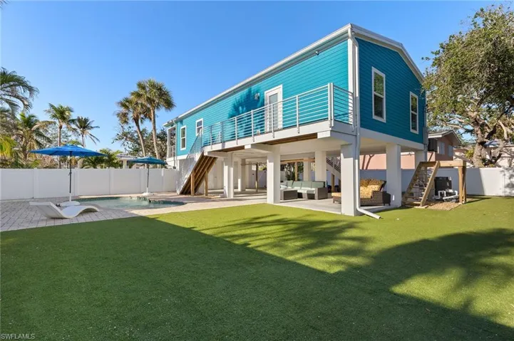 Back of property featuring a pool, an astroturf lawn, a patio, and an outdoor hangout area