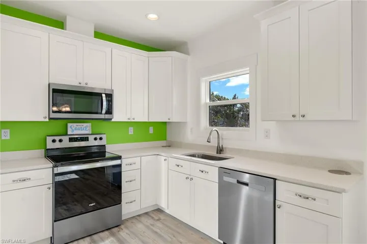 Kitchen with white cabinetry, sink, and stainless steel appliances