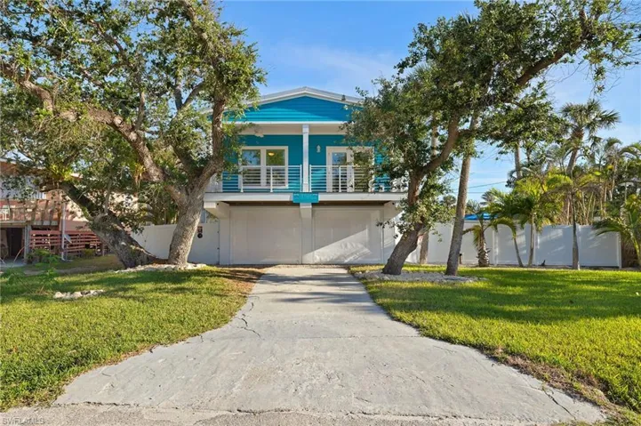 View of front of property featuring a garage, a balcony, and a front lawn
