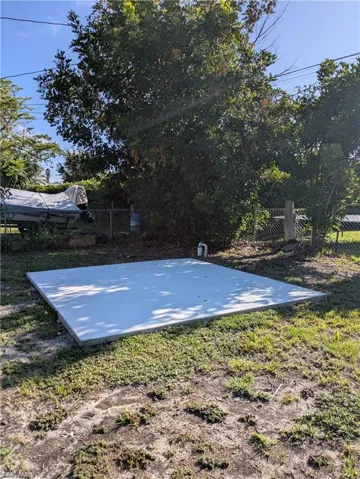 Concrete pad on a grassy lot, featuring established perimeter foliage