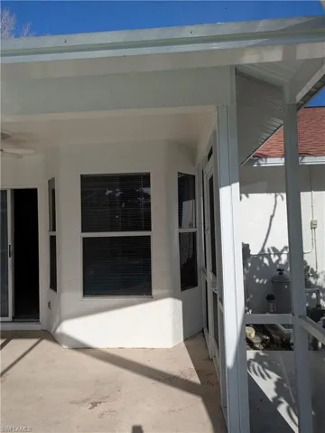 Screened-in patio featuring a ceiling fan, concrete flooring, and a bay window