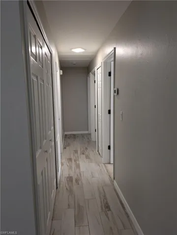 Hallway featuring wood-finish flooring, white panel doors, recessed lighting, and neutral wall tones